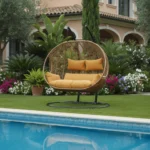 Balançoire Orvella 2 places avec coussin camel dans un jardin de villa, cadre métal noir et panier en rotin synthétique