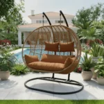 Balançoire Orvella 2 places avec coussin marron dans un jardin, cadre métal noir et panier en rotin synthétique