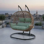 Balançoire Orvella 2 places avec coussin vert sauge sur une terrasse à Casablanca, cadre métal noir et panier en rotin synthétique