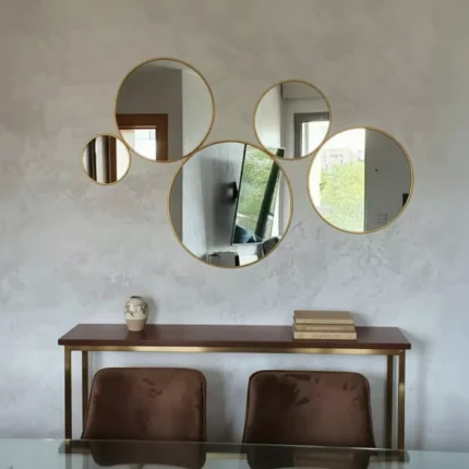 Vue de face d’un ensemble de 5 miroirs ronds en laiton doré au-dessus d’une table console, décoration murale chic pour salon marocain ou moderne