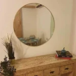 miroir rond en laiton doré vue légèrement de côté, posé sur une console en bois, fabrication artisanale au Maroc