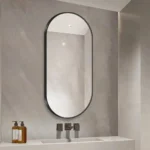 miroir semi-ovale cadre métal antirouille vu légèrement de biais, design moderne et résistant à l’humidité