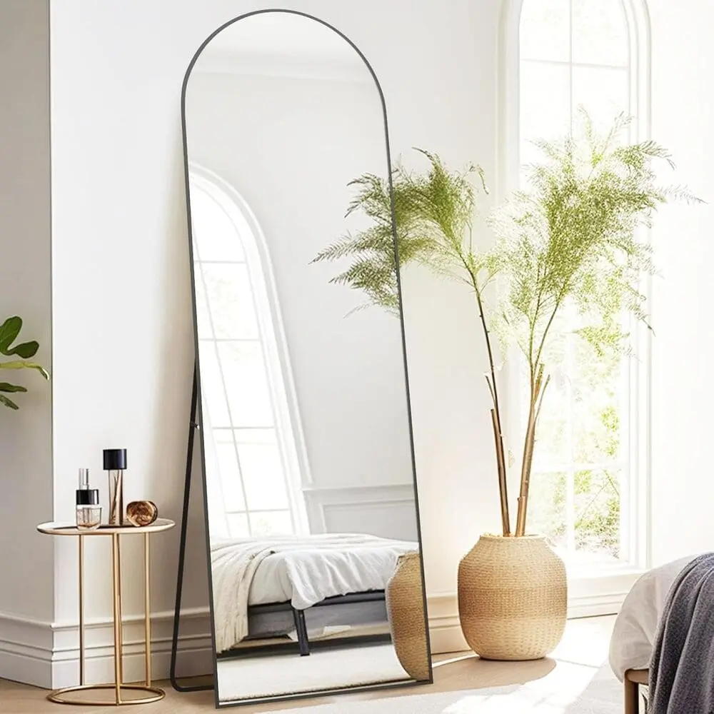 Miroir sur pied Arco – Vue légèrement de côté | Chambre et salon moderne miroir rectangulaire sur pied avec cadre métallique antirouille et sommet cintré, vue légèrement de côté, design moderne pour chambre ou salon