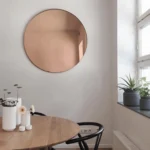 Miroir rose gold ROSEVEIL fixé sur un mur avec éclairage LED blanc, neutre et jaune pour salle de bain moderne et élégante.